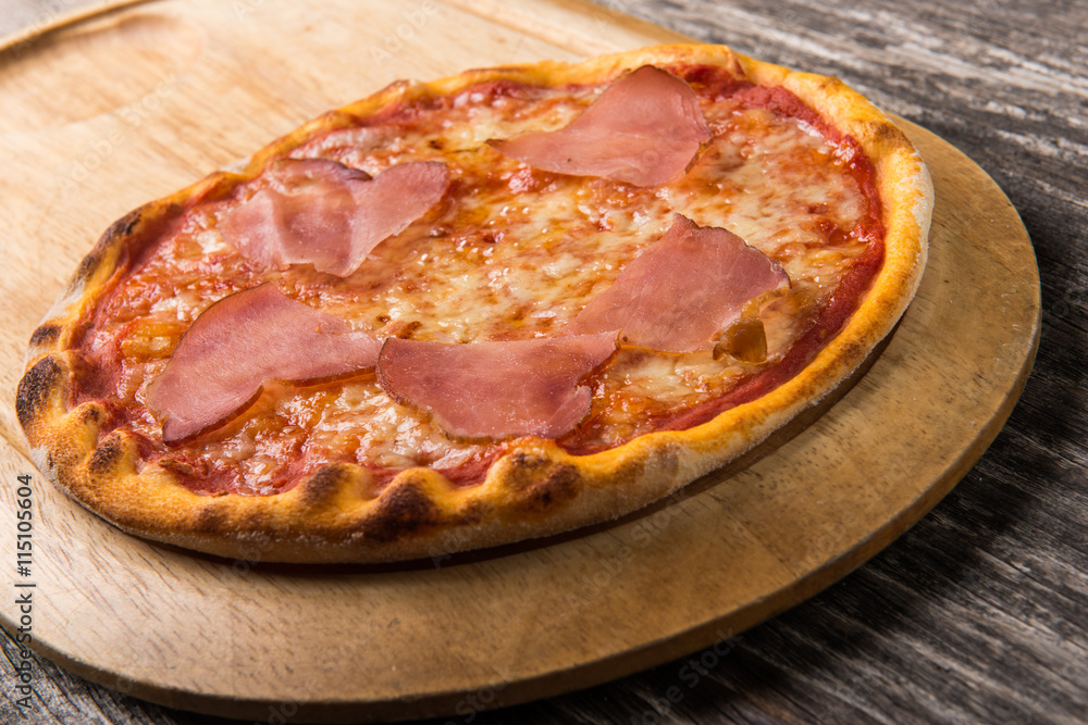 Pizza with proscuitto and cheese on rustic wooden cutting board