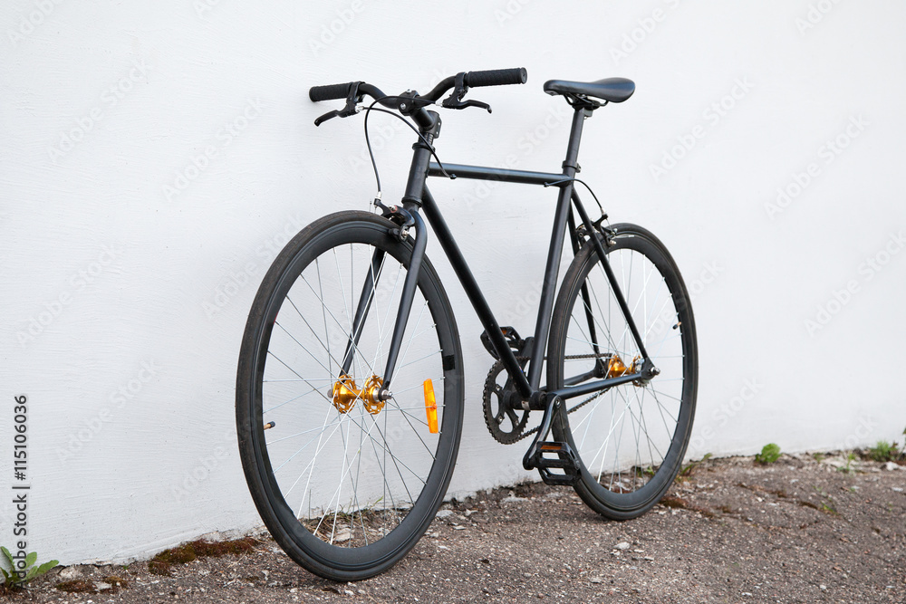 Black fixed-gear bicycle standing near gray wall Black fixed-gear bicycle standing near gray wall