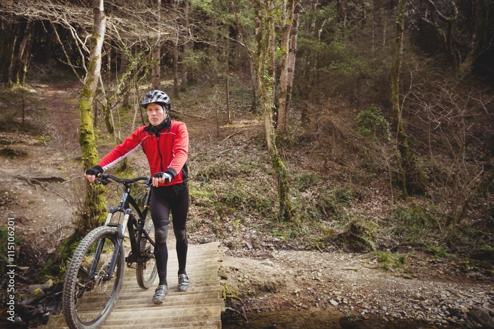Mountain biker walking with bicycle on footbridge Mountain biker walking with bicycle on footbridge