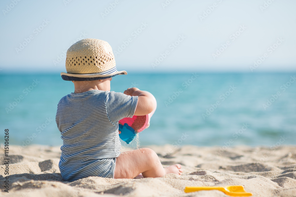 Cute baby boy playing with beach toys on tropical beach Cute baby boy playing with beach toys on tropical beach