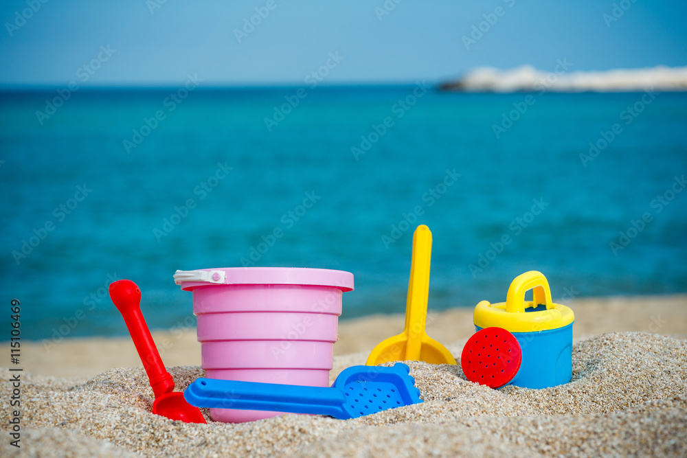 Children's beach toys - buckets, spade and shovel on sand on sunny day Children's beach toys - buckets, spade and shovel on sand on sunny day
