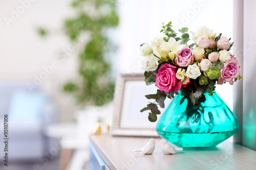 Beautiful bouquet of colourful roses in glass vase on table
