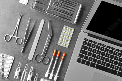 Medical tools set with laptop on dark gray background photo