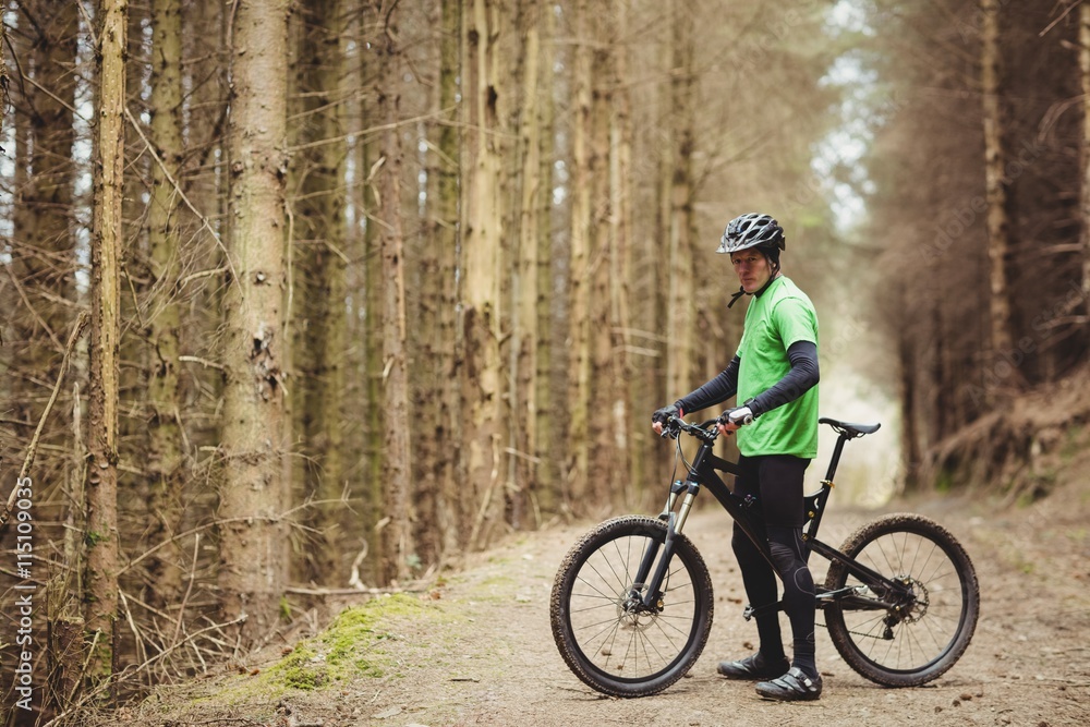Side view of mountain biker standing in forest Side view of mountain biker standing in forest