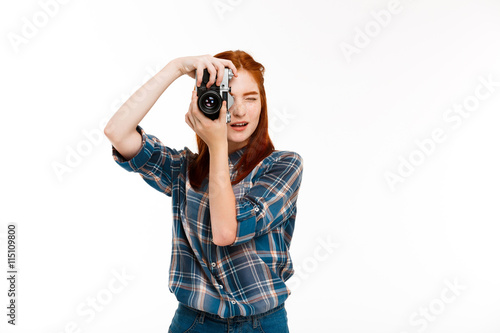 Portrait of young beautiful ginger photographer over white background.