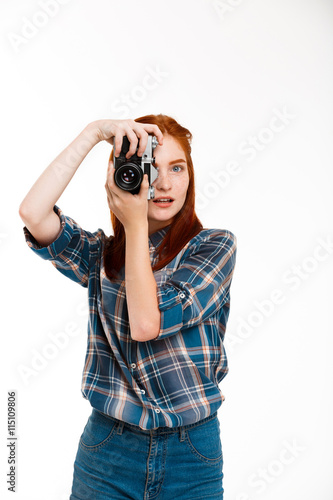 Portrait of young beautiful ginger photographer over white background.