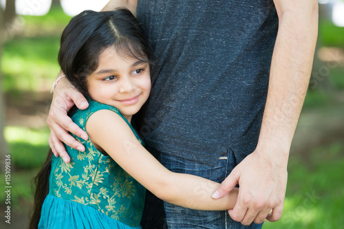 Closeup portrait, young child hugging her father tenderly, isolated outdoors outside green grass background. Daddy's little girl