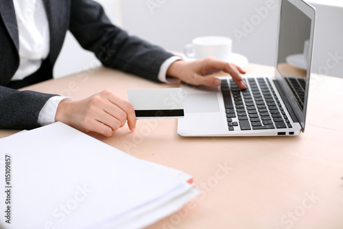 Close up of business woman hands using credit card and laptop computer