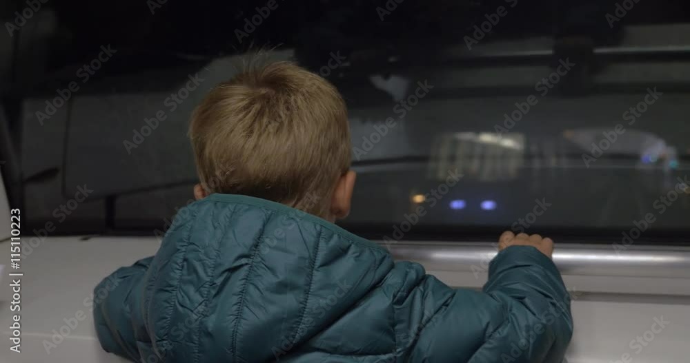 Back view of a little boy looking through the window of a moving subway train. On-coming train passing by in the tunnel Back view of a little boy looking through the window of a moving subway train. On-coming train passing by in the tunnel