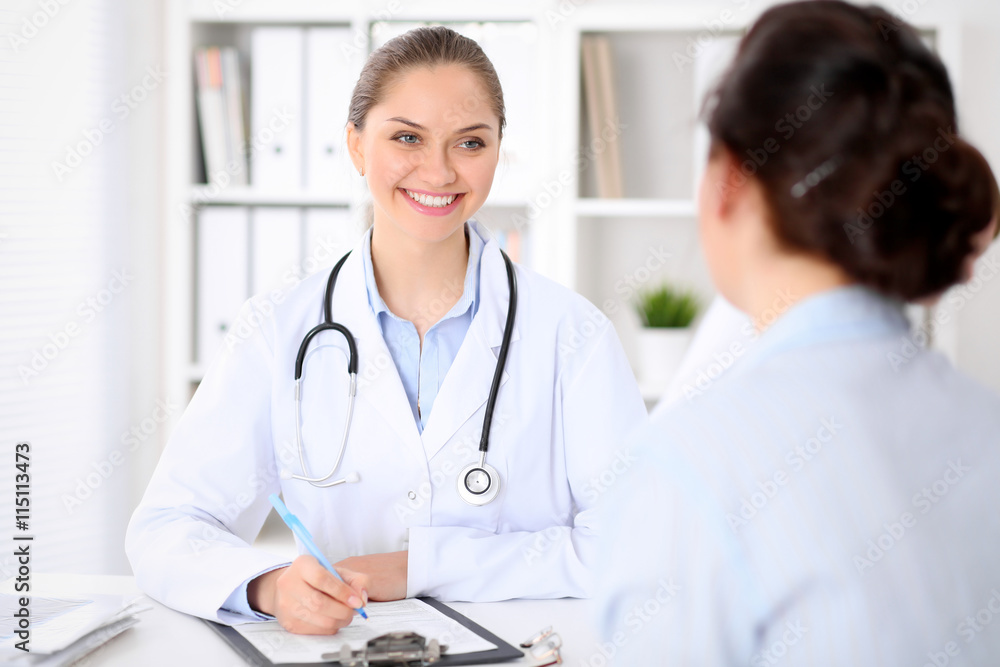 Friendly smiling doctor and patient sitting at the table. Very good news and high level medical service concept. Friendly smiling doctor and patient sitting at the table. Very good news and high level medical service concept.