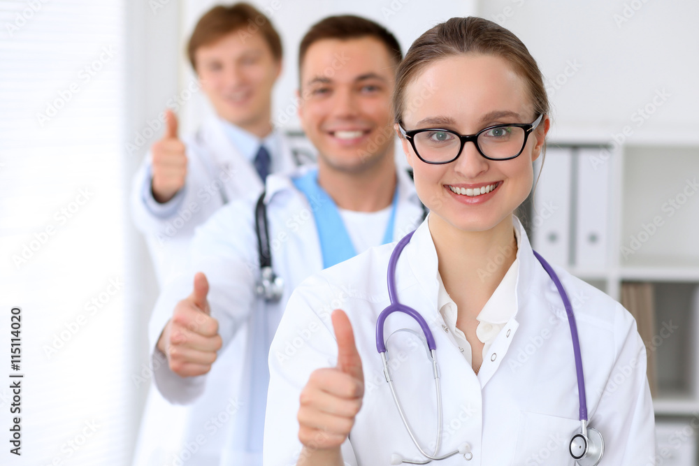 Happy doctor woman with medical staff at the hospital. Thumbs up Happy doctor woman with medical staff at the hospital. Thumbs up