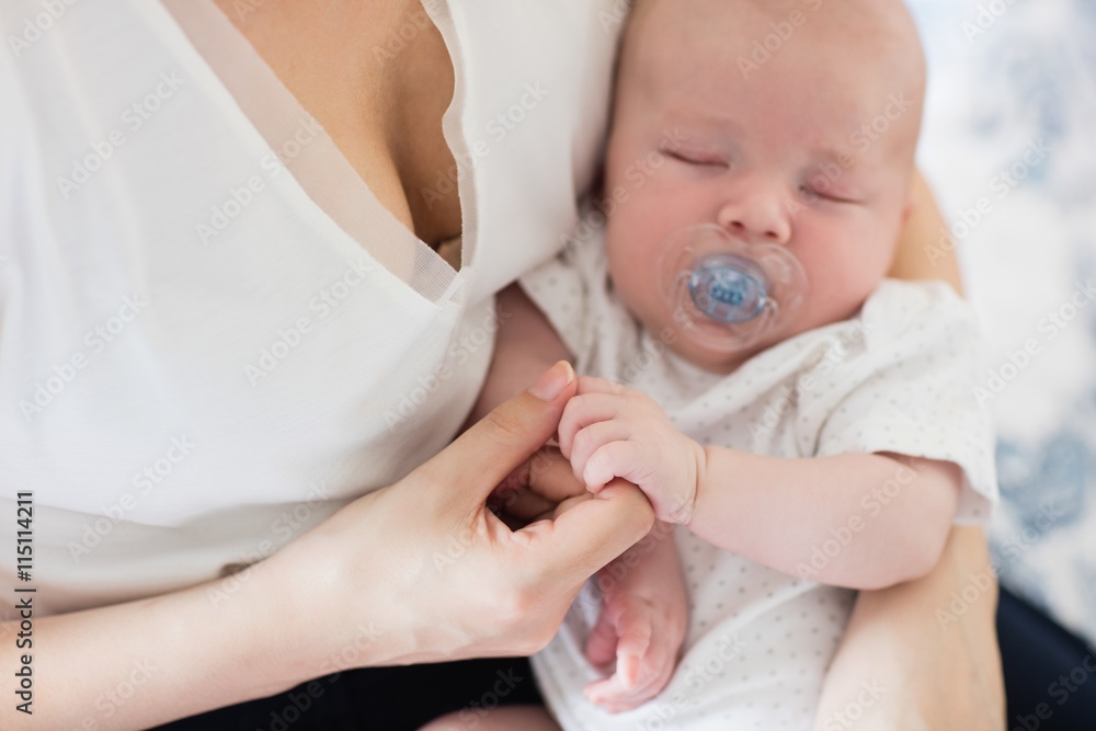 Close-up of baby with pacifier sleeping in mother's arms Close-up of baby with pacifier sleeping in mother's arms