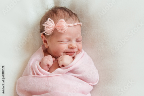 smiling newborn baby sleeping on white blanket