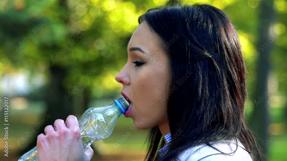 Slowmotion young beautiful woman stands and drinks from plastic bottle Slowmotion young beautiful woman stands and drinks from plastic bottle