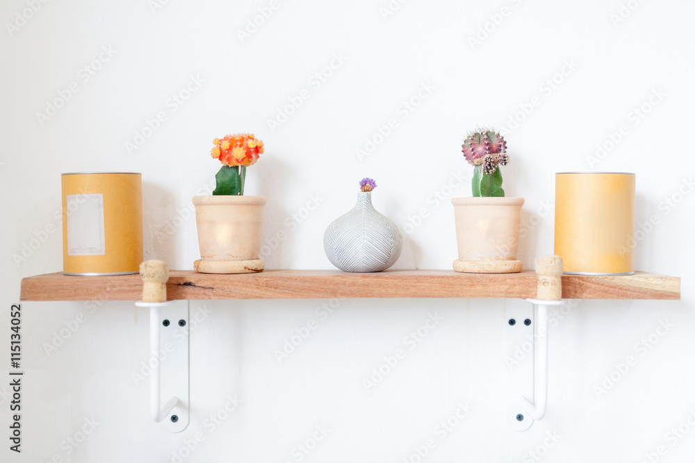 flowers and cup on a white wall shelf