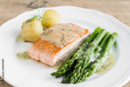 Grilled salmon with boiled potatoes and asparagus on white plate