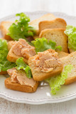 toasts with fish pate on white plate on white wooden background