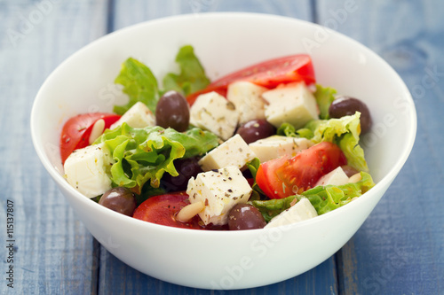 salad cheese with vegetables in white dish on blue background