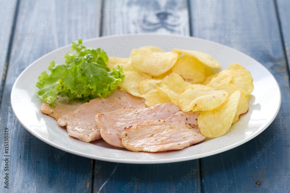 fried meat with chips and fresh lettuce on white dish