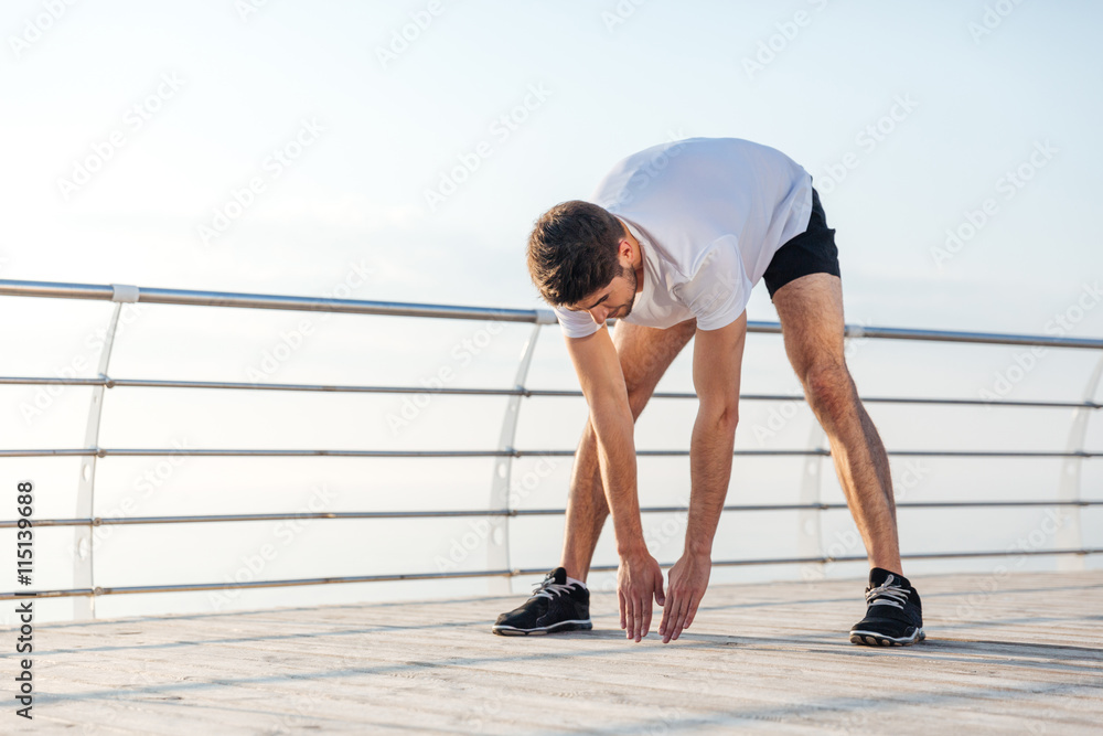 Male athlete stretching and warming up before jogging in morning