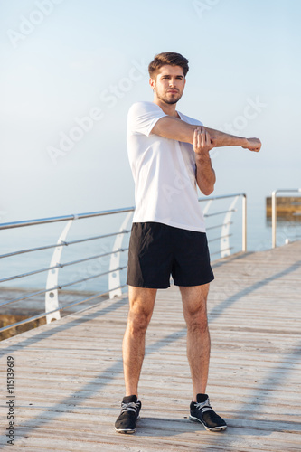 Fototapeta Naklejka Na Ścianę i Meble -  Sportsman standing and warming up on pier