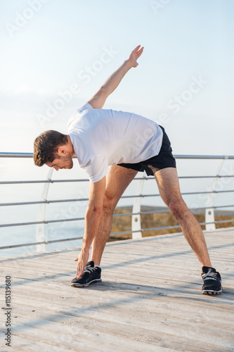 Serious young man athlete warming up and doing exercises