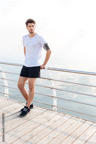 Sportsman standing at pier with armband and smartphone on hand © Drobot Dean