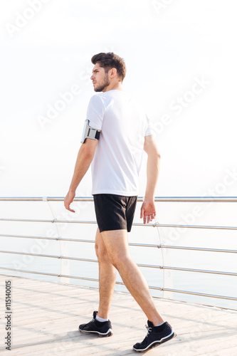 Sportsman with armband walking on pier