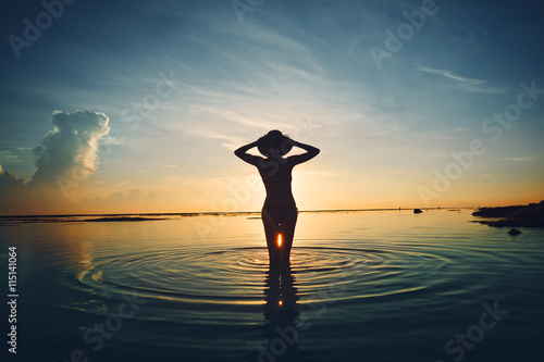 Silhouette of cheerful woman in the ocean meeting sunrise