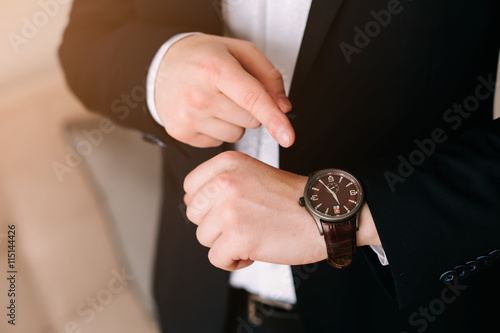 businessman in black suit look at his expensive swiss wristwatch on his hand and watching the time