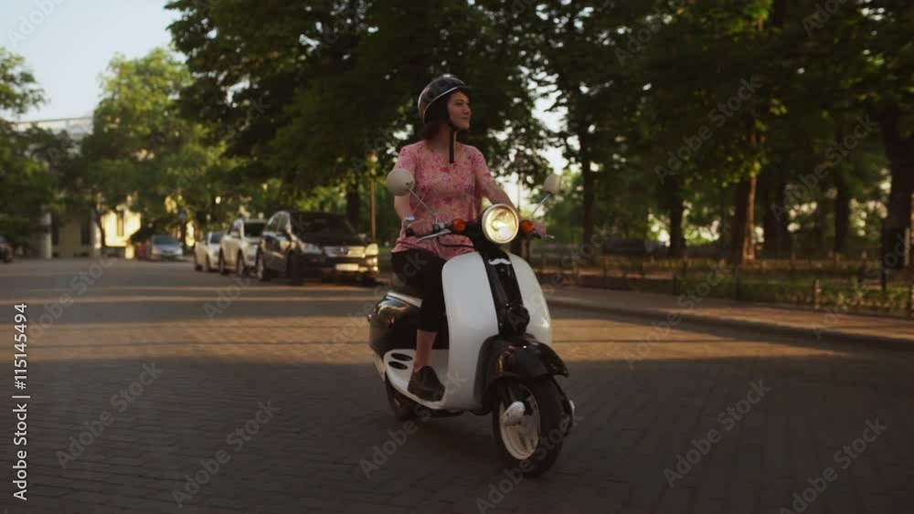 Young beautiful girl riding around city on scooter at sunrise. Slow motion. Young beautiful girl riding around city on scooter at sunrise. Slow motion.