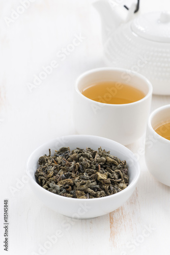 teapot and cups of green tea on a white wooden background