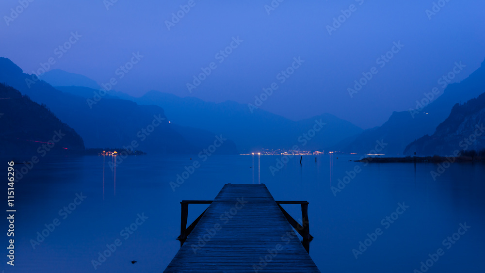 Panorama of mountain lake at sunset. Mountain range in the background. Wooden pier. - obrazy, fototapety, plakaty 