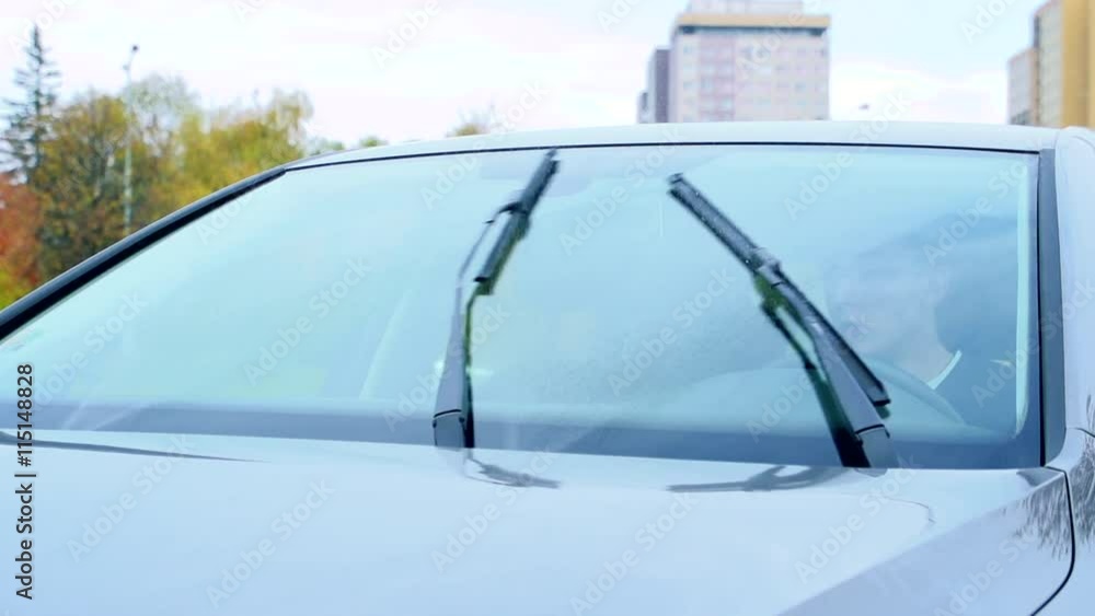 Slowmotion man sits in car where turns windscreen wipers Slowmotion man sits in car where turns windscreen wipers