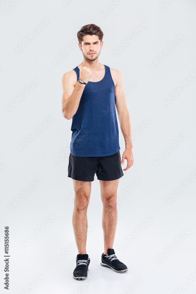 Angry sports man showing fist over gray background Angry sports man showing fist over gray background