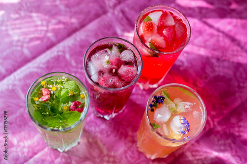 Four homemade refreshing summer cocktails and drinks with ice fresh berries, strawberry, raspberry and grapefruit on wooden cutting Board  