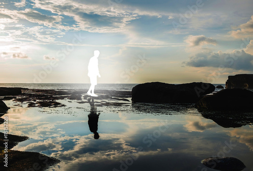 Silhouette white and bright man walking and black reflection on water, dark environment, vintage tone, selective focus