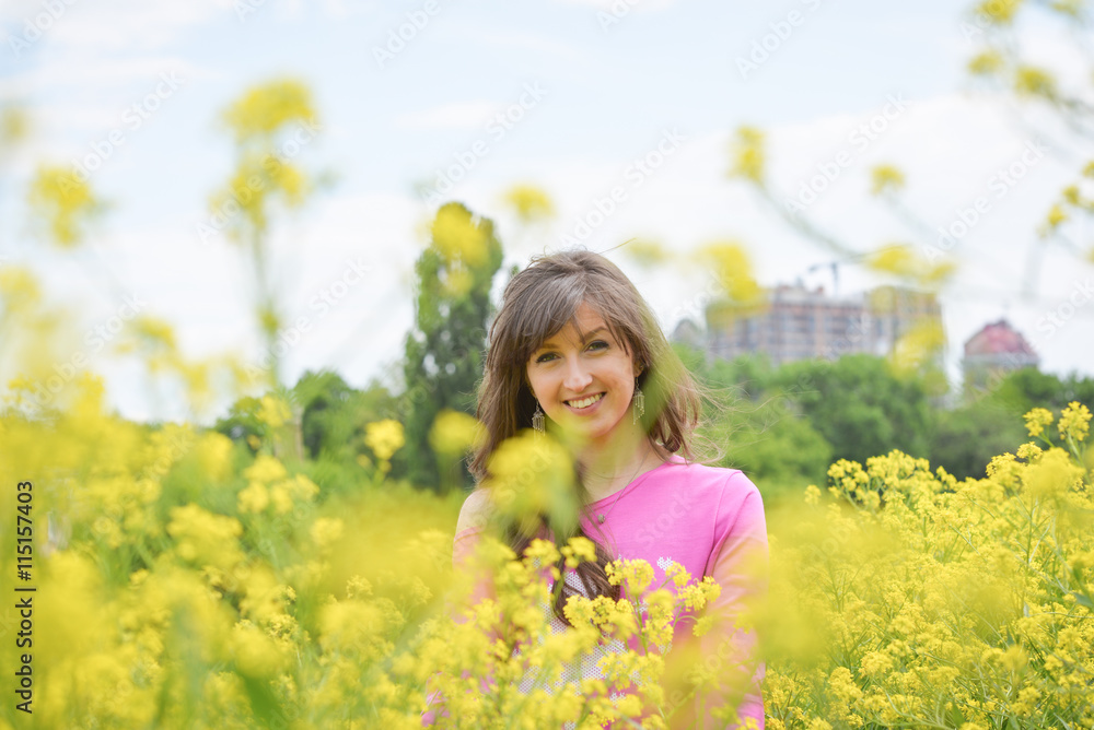 A beautiful young woman on a field. Stylish brunette girl standing in the yellow flower field on a sunny day in summer. Concept of freedom and happiness A beautiful young woman on a field. Stylish brunette girl standing in the yellow flower field on a sunny day in summer. Concept of freedom and happiness