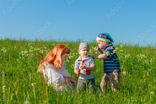 Beautiful red-haired mother playing with children in the field.