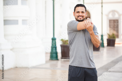Hispanic runner stretching his arms
