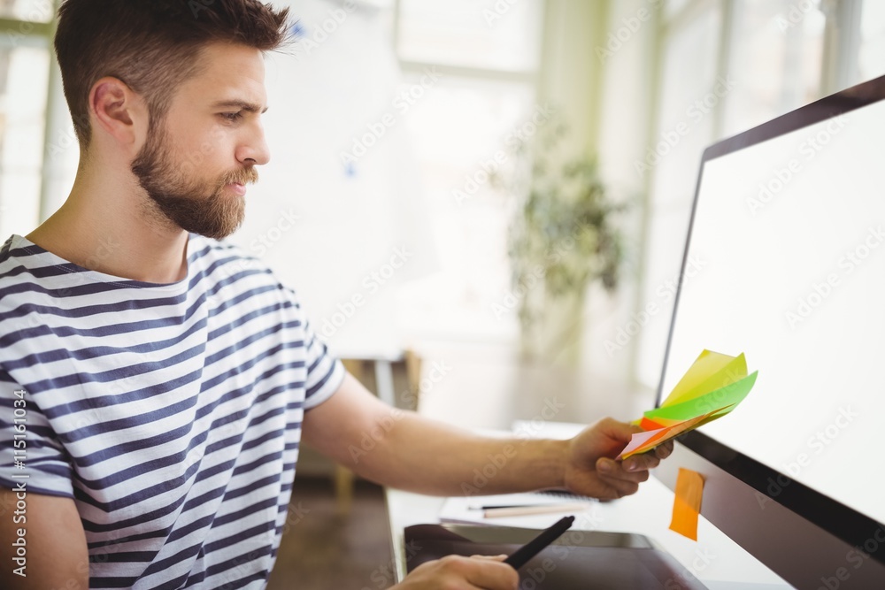 Fototapeta premium Businessman holding adhesive notes in creative office