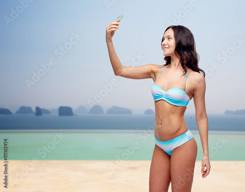 woman in swimsuit taking selfie with smatphone