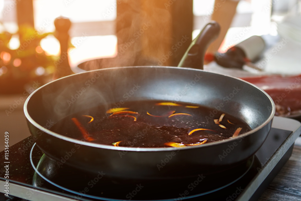 Frying pan with orange peel. Red liquid on frying pan. Red wine and orange rind. Just let it boil. Frying pan with orange peel. Red liquid on frying pan. Red wine and orange rind. Just let it boil.