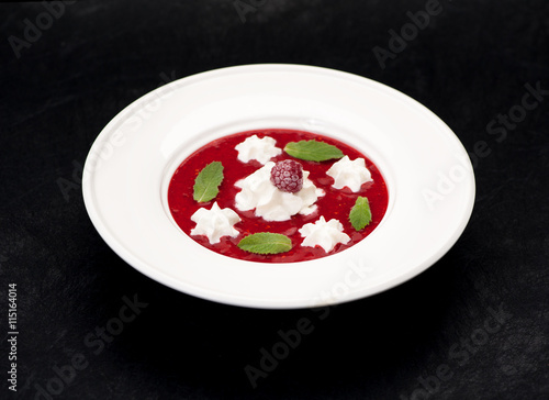 Cold soup with strawberries and raspberry or smoothie in a bowl on a black background