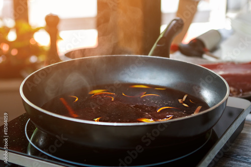 Frying pan with orange peel. Red liquid on frying pan. Red wine and orange rind. Just let it boil.