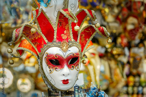 Typical vintage venetian red and golden mask, symbol Annual carnival, in souvenir shop on a street of Venice, Veneto, Italy.