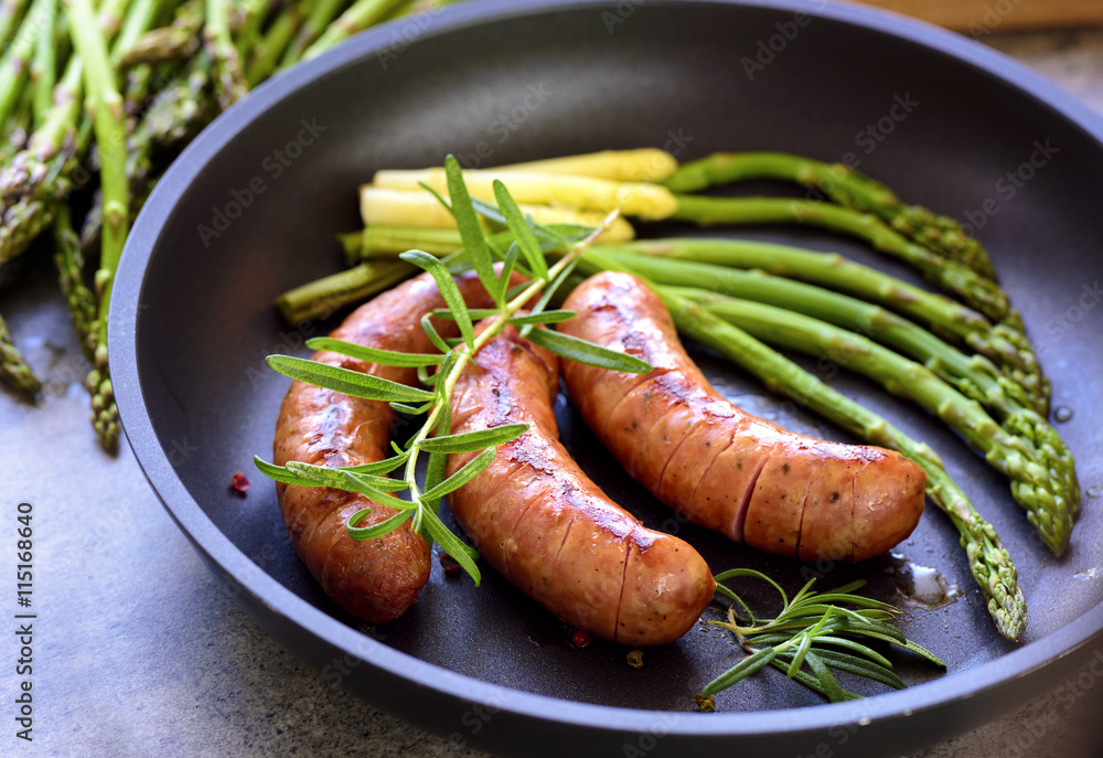 sausages with asparagus, tomatoes and rosemary on a pan