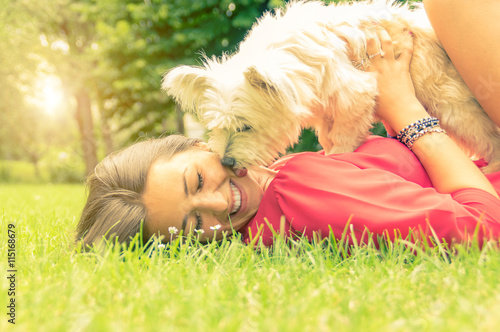 White dog kissing it's owner lying on the grass photo
