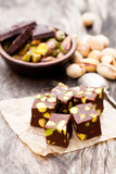 Dark  chocolate cubes with pistachios on wooden background