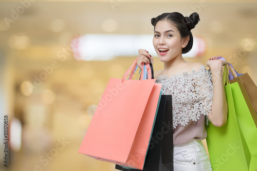 Attractive shopper woman holding shopping bags on salmon backgro